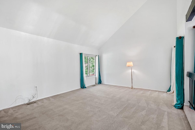 carpeted spare room featuring high vaulted ceiling
