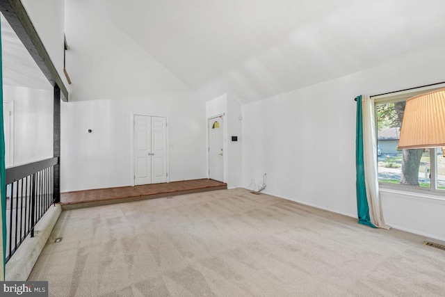 carpeted empty room featuring high vaulted ceiling