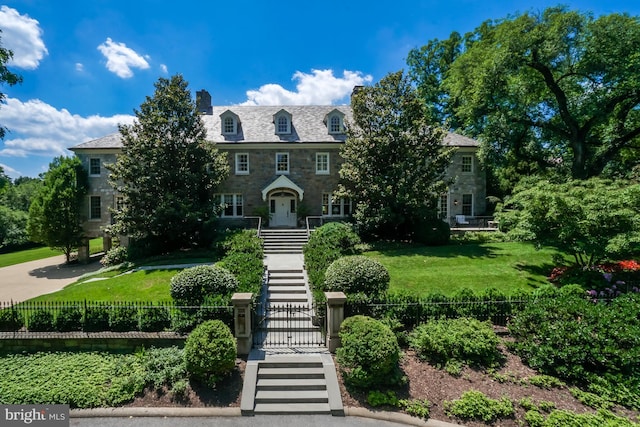 view of front of house with a chimney, stone siding, and a high end roof