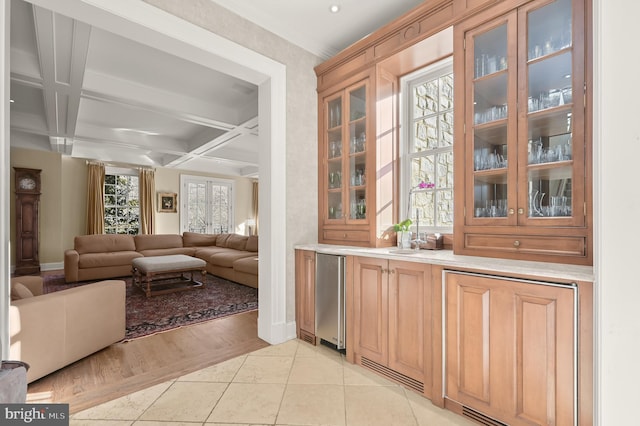 bar featuring baseboards, coffered ceiling, fridge, beam ceiling, and light tile patterned floors
