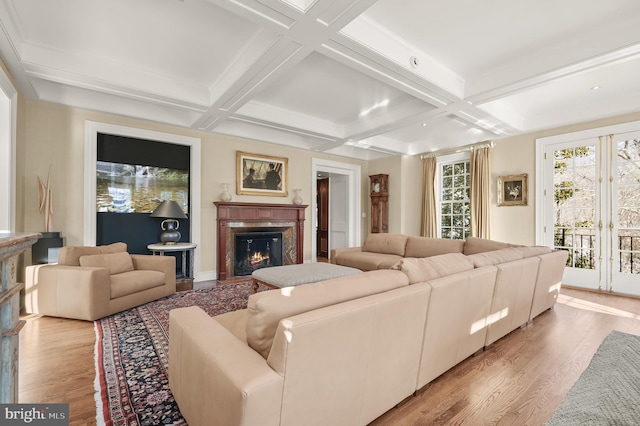 living room with a glass covered fireplace, coffered ceiling, light wood finished floors, beamed ceiling, and baseboards