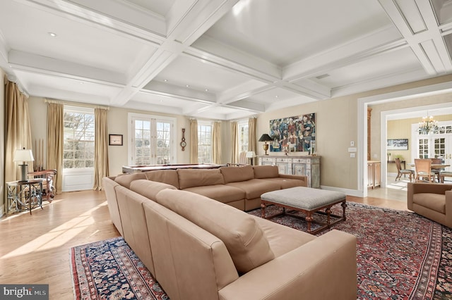 living room with coffered ceiling, light wood-type flooring, baseboards, a chandelier, and beam ceiling