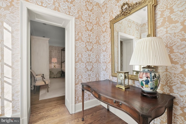 corridor featuring wood finished floors, wallpapered walls, an office area, and baseboards