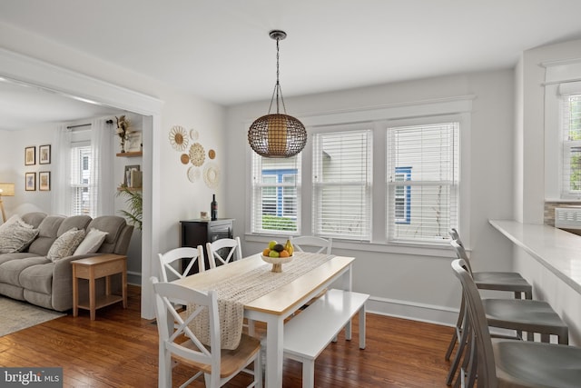dining space with wood-type flooring and baseboards