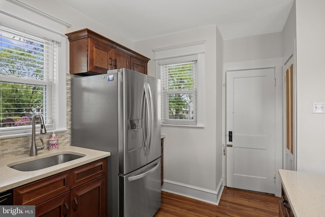 kitchen featuring a sink, stainless steel refrigerator with ice dispenser, dark wood-type flooring, and light stone countertops