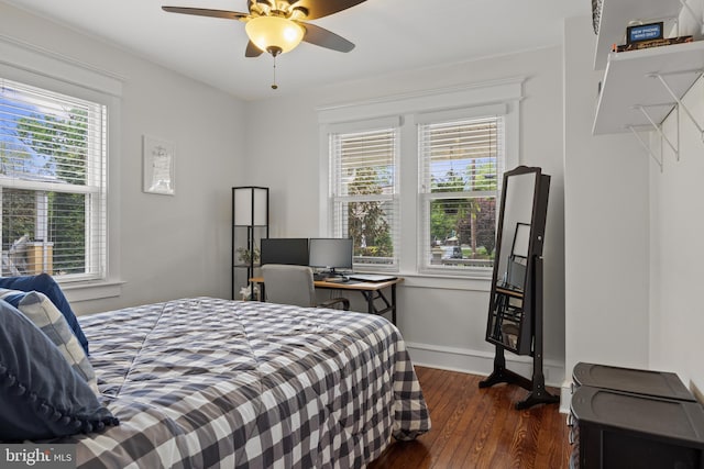 bedroom featuring dark wood-style floors, multiple windows, baseboards, and ceiling fan