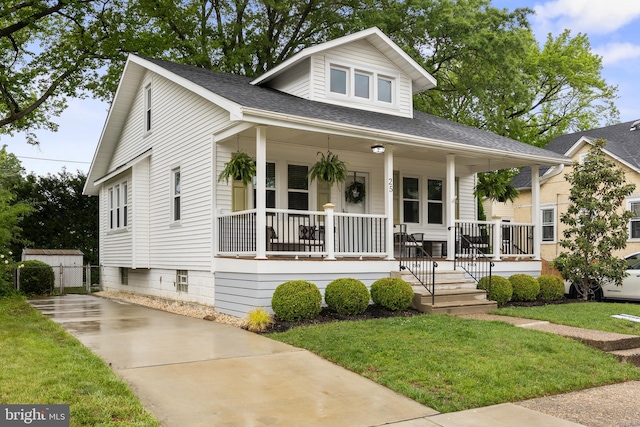 bungalow-style home with covered porch, a front lawn, and a shingled roof