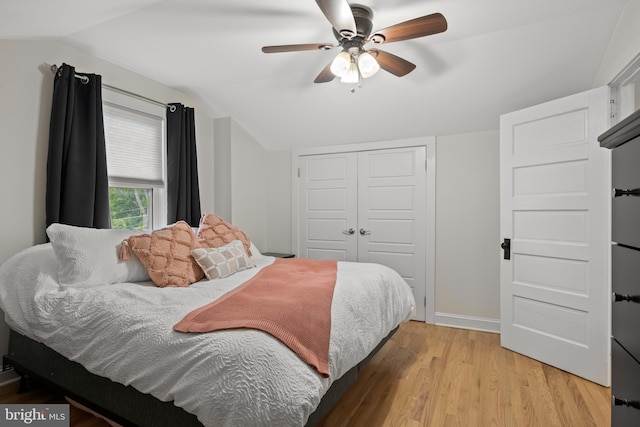 bedroom with vaulted ceiling, light wood-type flooring, a closet, baseboards, and a ceiling fan