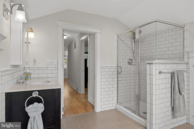 full bath featuring a stall shower, lofted ceiling, and vanity