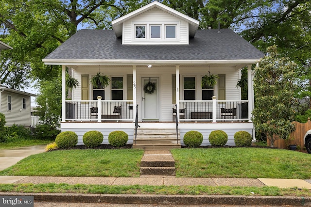 bungalow-style house with a shingled roof, a front lawn, and a porch