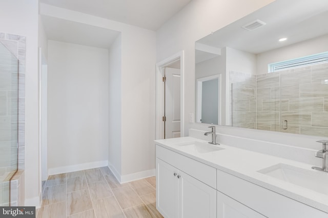 full bath featuring a stall shower, baseboards, and double vanity