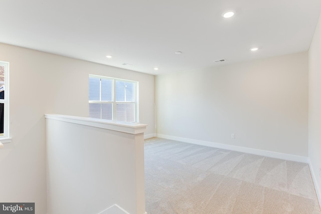 spare room featuring light carpet, recessed lighting, and baseboards