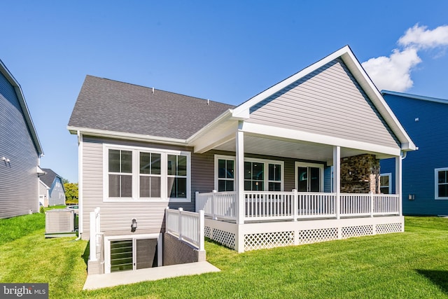 rear view of property with a porch, a yard, a shingled roof, and central AC