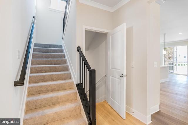 staircase with wood finished floors, baseboards, crown molding, and recessed lighting