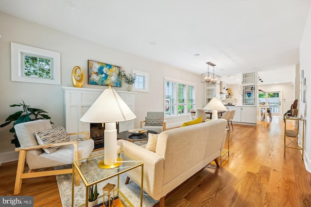 203 Spring Ave, Takoma Park, MD 20912 - living area featuring light wood-style flooring, a brick fireplace, a chandelier, and baseboards
