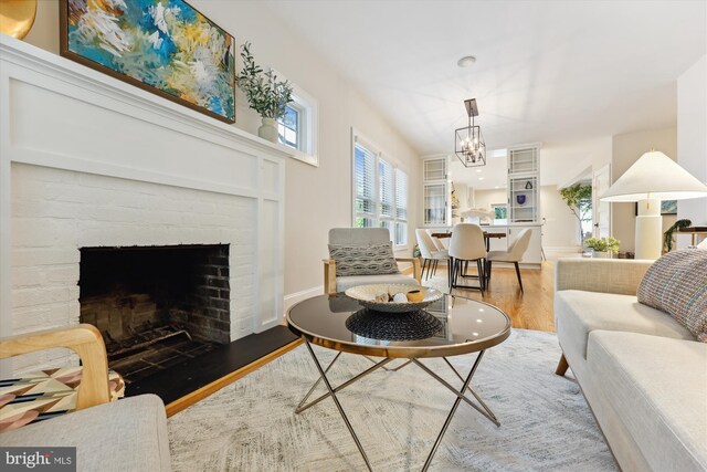 203 Spring Ave, Takoma Park, MD 20912 - living area featuring wood finished floors, plenty of natural light, a brick fireplace, and a chandelier