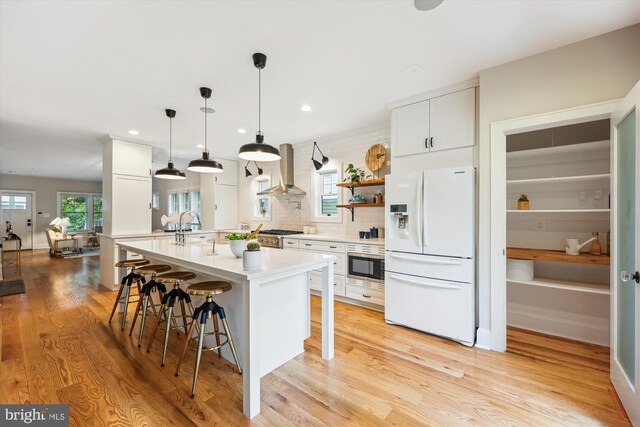 203 Spring Ave, Takoma Park, MD 20912 - kitchen with white fridge with ice dispenser, wall chimney exhaust hood, a kitchen breakfast bar, light countertops, and light wood-style flooring