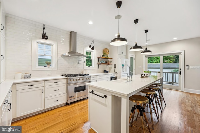 203 Spring Ave, Takoma Park, MD 20912 - kitchen featuring premium range, wall chimney exhaust hood, a sink, a breakfast bar area, and white cabinets