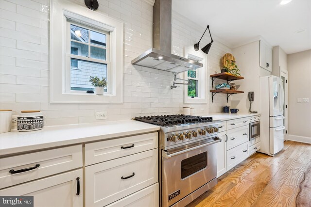 203 Spring Ave, Takoma Park, MD 20912 - kitchen with wall chimney exhaust hood, stainless steel appliances, backsplash, and light wood-style flooring