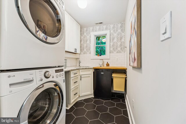 203 Spring Ave, Takoma Park, MD 20912 - washroom featuring estacked washer and dryer, dark tile patterned flooring, and cabinet space