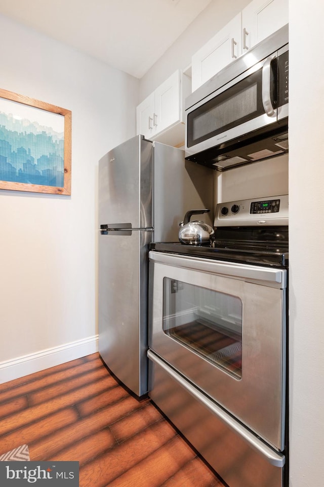 kitchen featuring stainless steel appliances, baseboards, dark wood-type flooring, and white cabinets