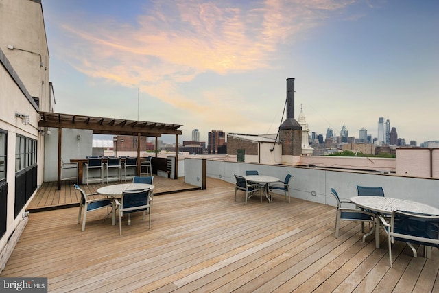 wooden terrace with outdoor dining space and a view of skyline
