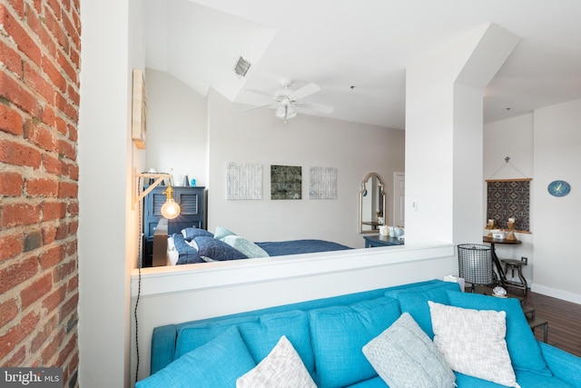 living area with wood finished floors, ceiling fan, brick wall, and baseboards