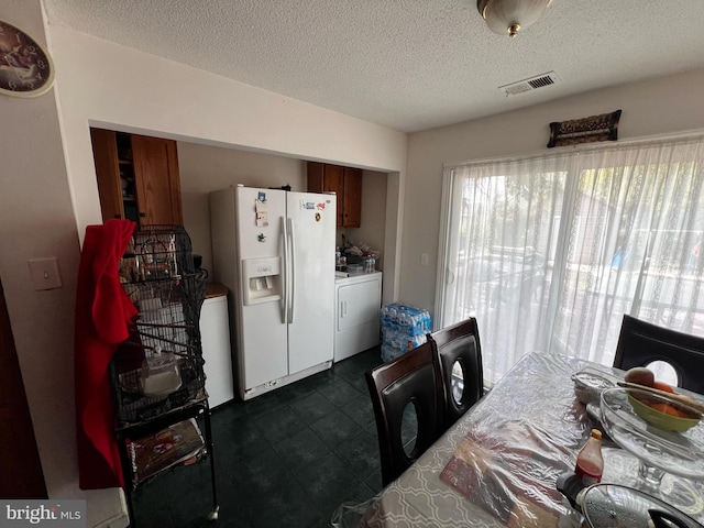 dining area featuring a textured ceiling, independent washer and dryer, and dark tile patterned flooring
