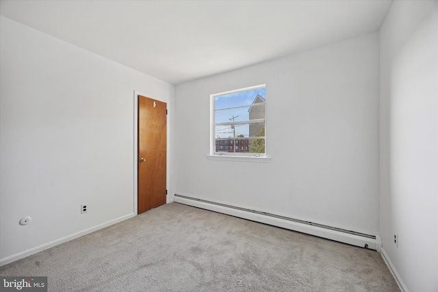 spare room featuring a baseboard radiator, carpet flooring, and baseboards