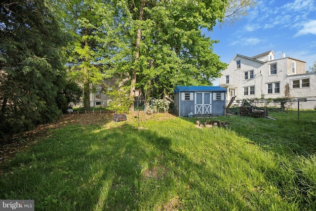 view of yard with a storage shed, fence, and an outbuilding