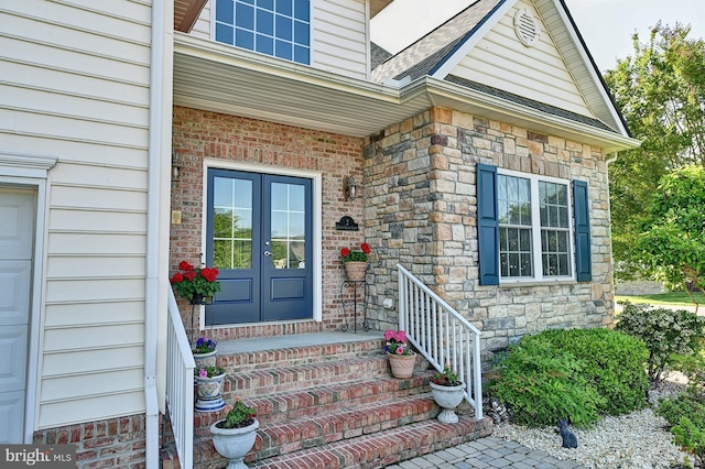property entrance with french doors, stone siding, and roof with shingles