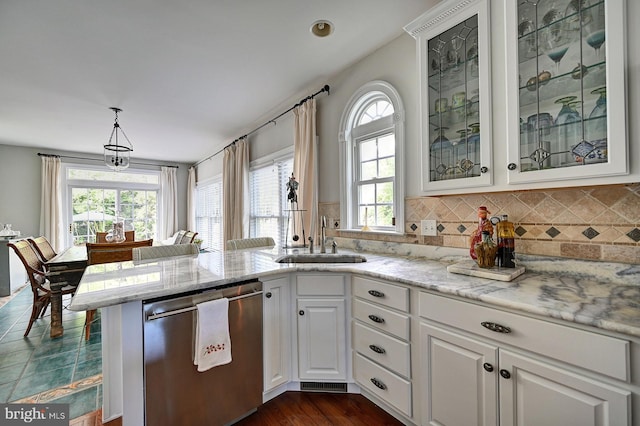 kitchen with stainless steel dishwasher, a sink, plenty of natural light, and white cabinetry