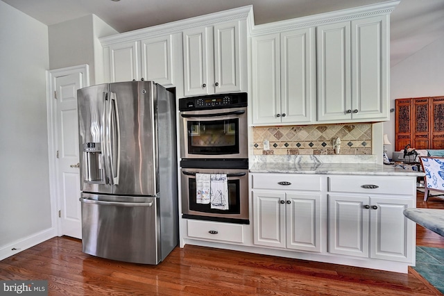 kitchen featuring appliances with stainless steel finishes, tasteful backsplash, white cabinets, dark wood-style flooring, and light stone countertops