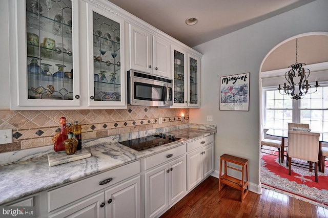 kitchen featuring stainless steel microwave, black electric cooktop, a chandelier, dark wood-type flooring, and white cabinets