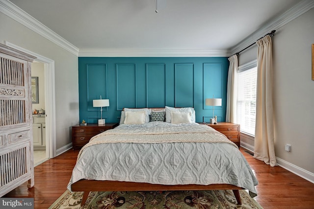 bedroom with ornamental molding, wood finished floors, baseboards, and ensuite bath