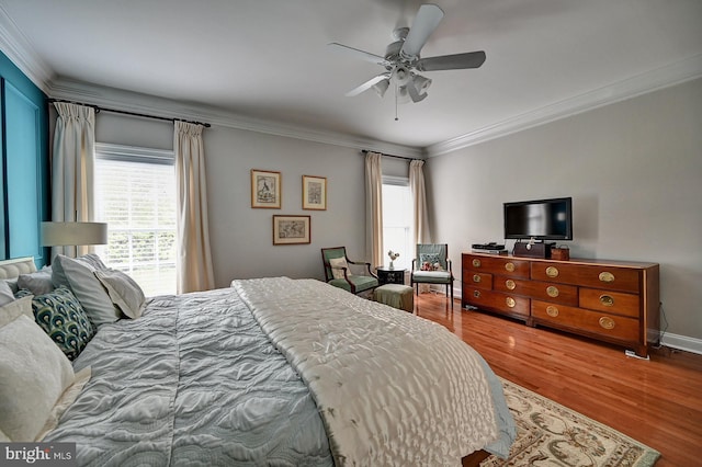 bedroom with ornamental molding, multiple windows, wood finished floors, and a ceiling fan