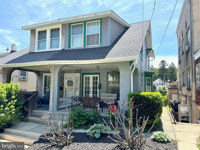 view of front of property featuring french doors, a shingled roof, and covered porch