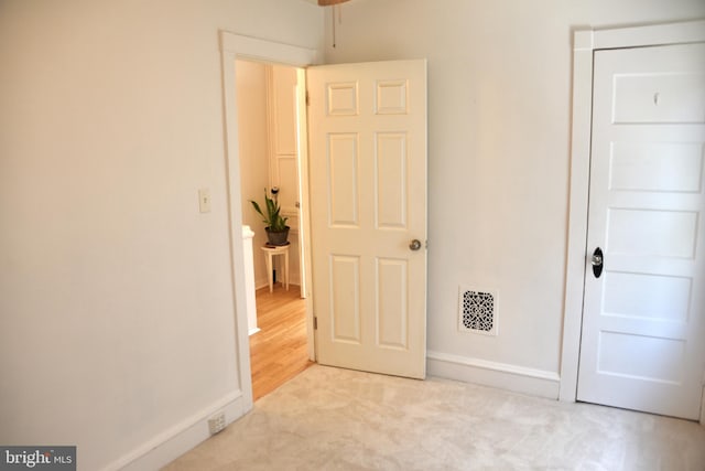 unfurnished bedroom featuring baseboards, light carpet, and a closet