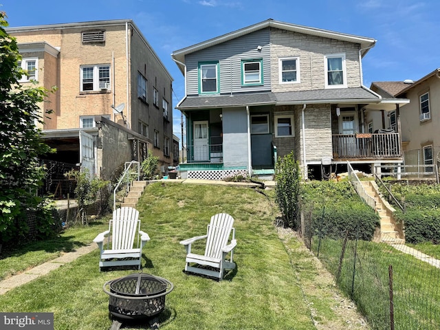 view of front facade featuring a fire pit, stone siding, a porch, and stairway