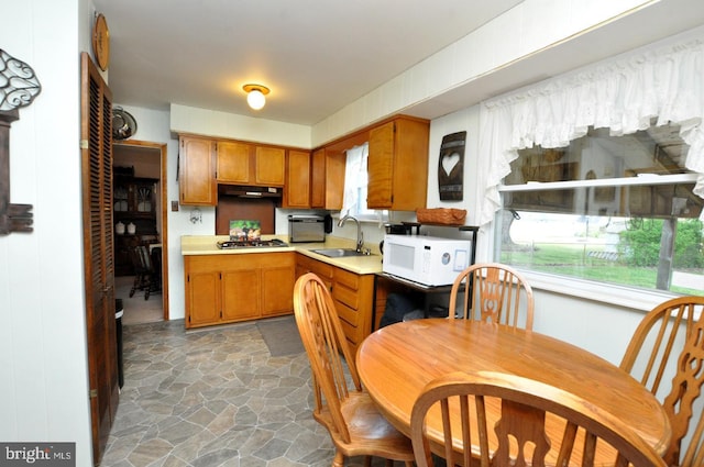 400 S Arthur Dr, Edgewater Park, NJ 08010 - kitchen with white microwave, a sink, under cabinet range hood, stainless steel gas stovetop, and brown cabinets
