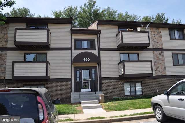 view of building exterior featuring entry steps and uncovered parking