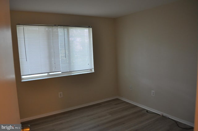 spare room featuring wood finished floors, baseboards, and plenty of natural light