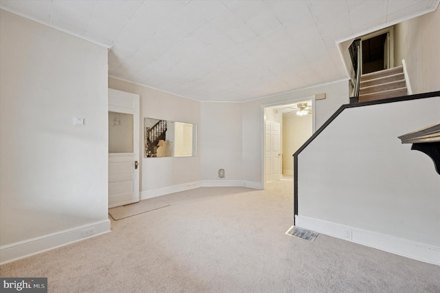 basement with ornamental molding, carpet flooring, stairs, baseboards, and a ceiling fan