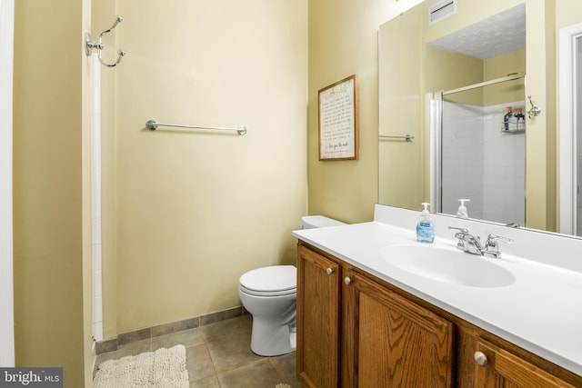 bathroom with toilet, tiled shower, tile patterned floors, vanity, and baseboards