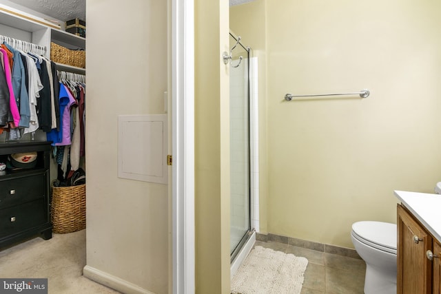 full bathroom featuring a stall shower, vanity, a spacious closet, toilet, and baseboards