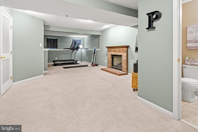 workout room with carpet floors, baseboards, a fireplace, and a textured ceiling