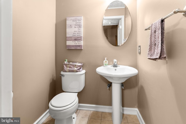 bathroom with baseboards, toilet, and tile patterned floors