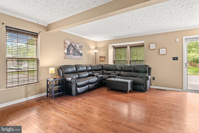 living room with light wood-type flooring, crown molding, a textured ceiling, and baseboards
