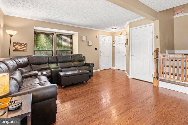 living room featuring a textured ceiling, wood finished floors, crown molding, and baseboards