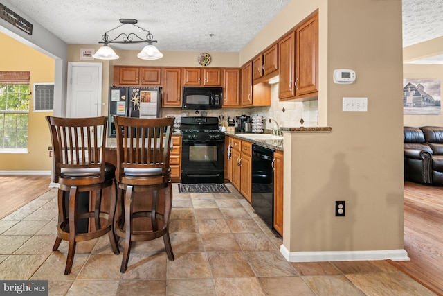 kitchen with black appliances, a sink, baseboards, backsplash, and a textured ceiling